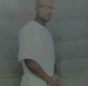 John McGraw standing in a white T-shirt beside a grey wall
