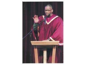Tony Smith speaking at a lectern in a red robe