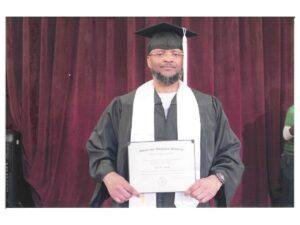 Tony Smith wearing a graduation cap and gown and holding his certificate