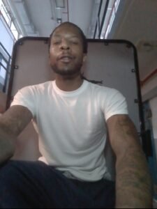 Joshua Carse in a white shirt with his hair pulled back
