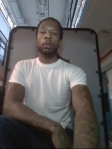 Joshua Carse seated with his hair pulled back
