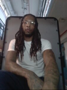 Joshua Carse seated wearing glasses and a white shirt